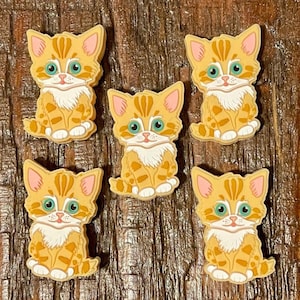 May include: Six orange and white cartoon kitten charms with green eyes. The kittens are sitting with their paws tucked under them.