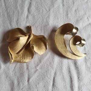 May include: A set of three ceramic mugs with a speckled, matte finish. The mugs are in shades of cream, light brown, and dark brown. Each mug has a simple, minimalist design, perfect for coffee or tea.