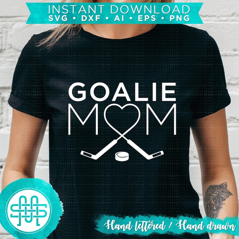 Puede incluir: Una camiseta negra con un dise&ntilde;o blanco que dice "Goalie Mom" con un coraz&oacute;n y palos de hockey. El texto "Hand lettered/Hand drawn" est&aacute; en la parte inferior del dise&ntilde;o.