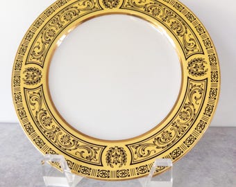 May include: A gold and black decorative plate with a floral design. The plate is on a white background.
