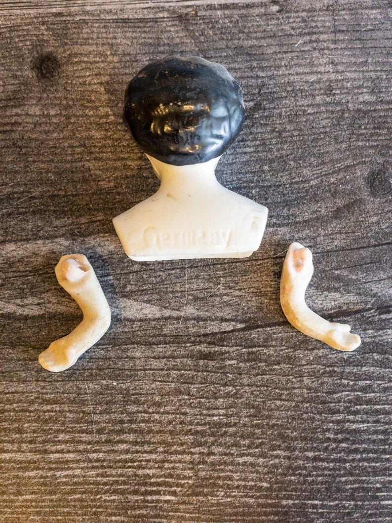 以下が含まれることがあります： 黒い髪の白い陶器のドールヘッドと、白い陶器の胴体。胴体には「Germany」と刻印されています。陶器の腕が2本付属しています。