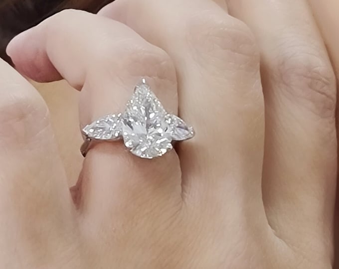 This Unique Three Stone Ring features a 4 Carat Teardrop IGI Certified CVD lab grown diamond accentuated with 1.20ct tapered baguette side stones