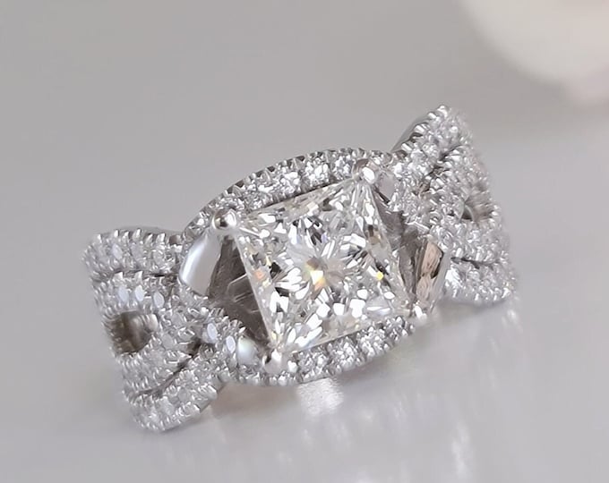 This unique twisted 14K white gold setting features a 2 carat princess cut IGI certified CVD lab grown diamond and 0.30ct princess cut side diamonds accompanied by a flushing matching 0.70 carats wedding bands