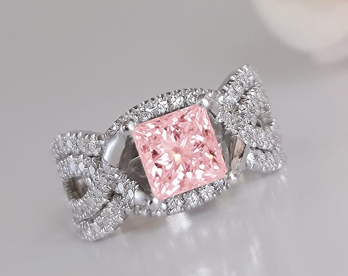 This unique twisted 14K white gold setting features a 1.5 carat pink princess cut IGI certified CVD lab grown diamond and 0.30ct princess cut side diamonds accompanied by a flushing matching 0.70 carats wedding bands