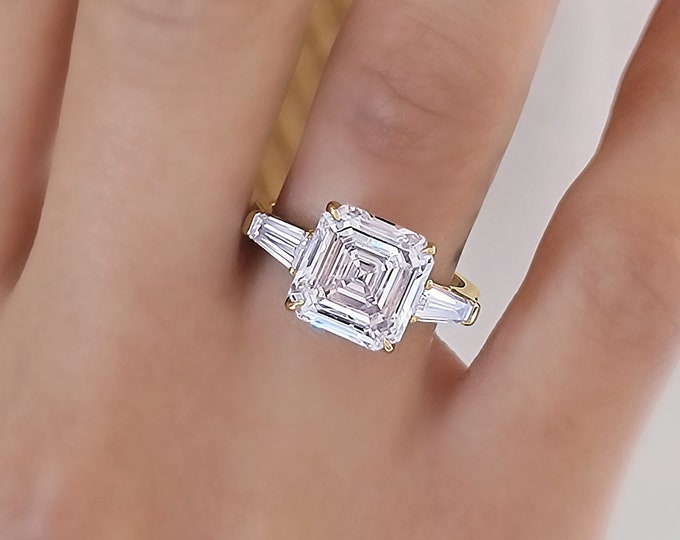 This timeless classic 3 stone ring features a 5 Carat Asscher Cut IGI certified CVD lab grown Diamond and 0.70 carats tapered baguette side stones