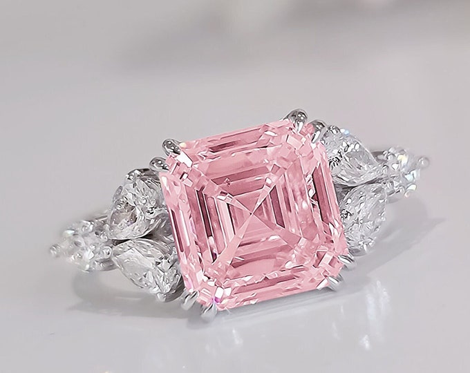 This timeless classic cluster diamond ring features a 5 Carat Pink Asscher Cut IGI certified CVD lab grown Diamond and 0.96 carats pear cut diamond side stones