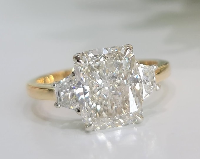 This Unique Three Stone Ring features a 3  Carat Radiant Cut IGI Certified CVD lab grown diamond accentuated with 0.50ct trapezoid cut side stones