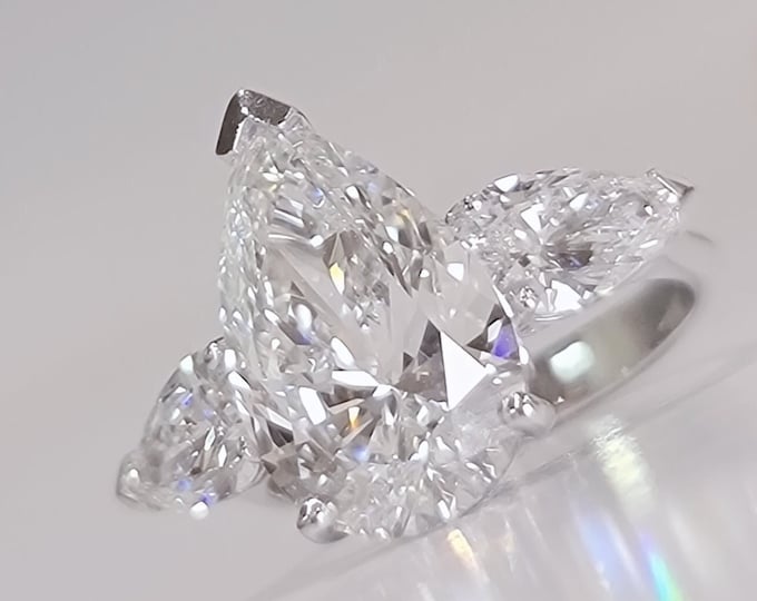 This Unique Three Stone Ring features a 4 Carat Teardrop IGI Certified CVD lab grown diamond accentuated with 1.20ct tapered baguette side stones