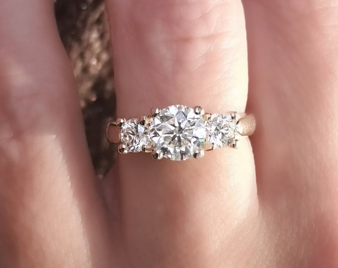 This Classic 14K yellow gold Three Stone Engagement Ring features a 1.30 carat Ideal round cut diamond and 0.70 carats round brilliant side diamonds