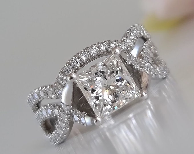 This unique twisted 14K white gold setting features a 2 carat princess cut IGI certified CVD lab grown diamond and 0.30ct princess cut side diamonds accompanied by a flushing matching 0.35 carats wedding band