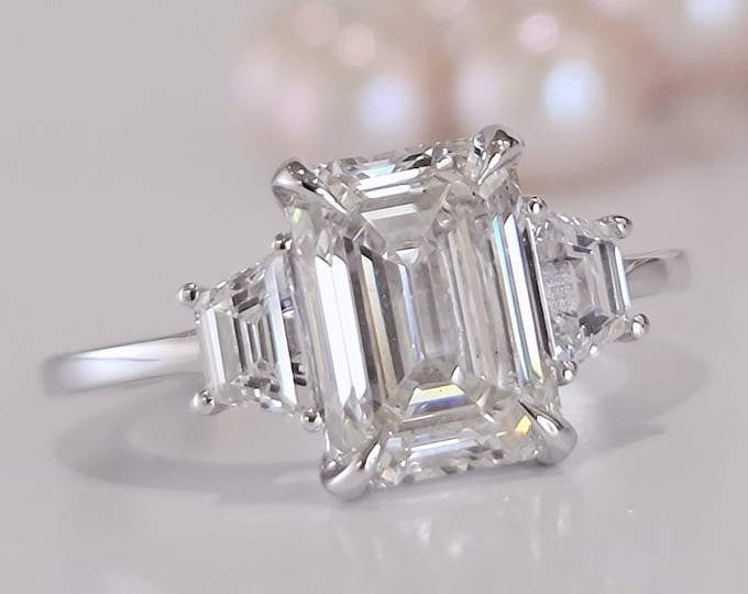 Unique Three Stone Engagement Ring set with a 3 carat IGI Certified CVD lab grown Emerald Cut Diamond accentuated with 0.70 carats trapezoid step cut side diamonds