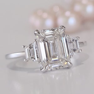 エレガントな 3 カラットのエメラルド カット ダイヤモンド リング - 0.70CT 台形サイド ストーン、IGI 認定、3 石 CVD ラボ グロウン エンゲージ リング