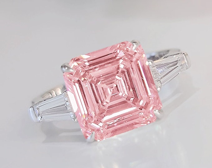 This timeless classic 3 stone ring features a 5 Carat Pink Asscher Cut IGI certified CVD lab grown Diamond and 0.70 carats tapered baguette side stones