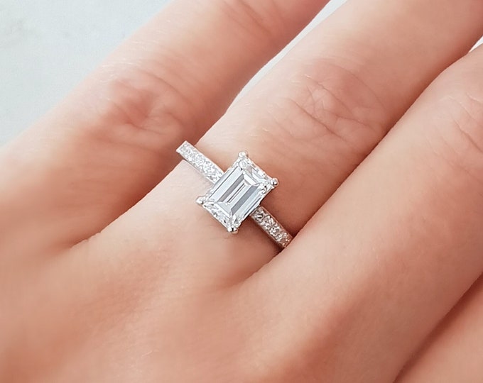 This timeless pave set solitaire diamond ring features a 1.50 carat Emerald Cut IGI certified CVD lab grown diamond & 0.14 carats accent diamonds
