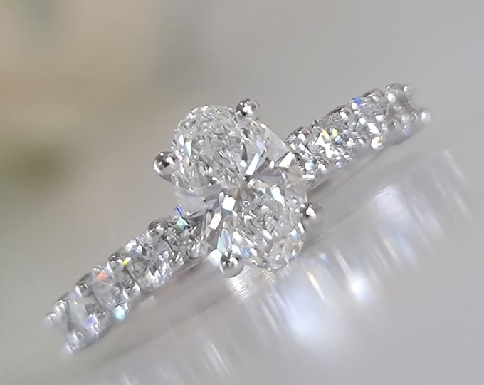 This unique oval ring with side diamonds features a 1.10 carat center oval cut IGI certified CVD lab grown diamond set with 0.90 carats side diamonds