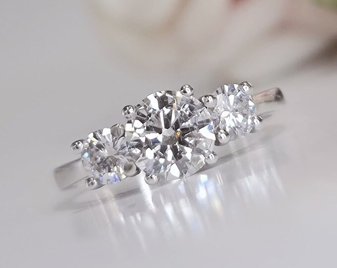 This Unique Three Stone Ring features a 1 Carat Round Cut IGI Certified CVD lab grown diamond accentuated with 0.50 carats round cut side stones