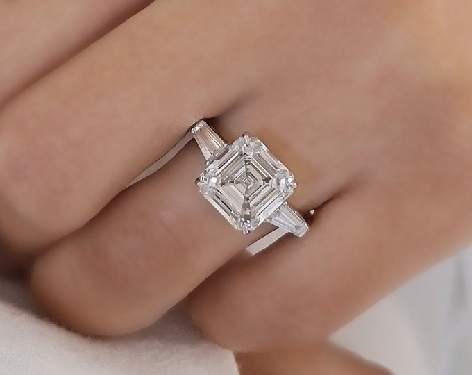 This timeless classic 3 stone ring features a 5 Carat Asscher Cut IGI certified CVD lab grown Diamond and 0.70 carats tapered baguette side stones