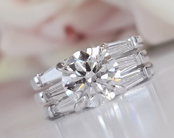 This classic timeless three Stone Diamond Ring features a 2.5 Carat Ideal Round Brilliant Cut IGI Certified CVD lab grown diamond accentuated with 0.50ct tapered baguette side stones accompanied by 2 matching 0.70 carats baguette flushing wedding bands
