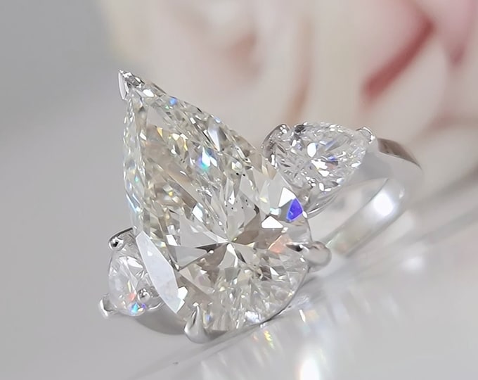 This Unique Three Stone Ring features a 6 Carat Teardrop IGI Certified CVD lab grown diamond accentuated with 1 carat pear cut side diamonds