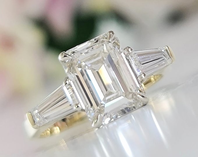 A timeless classic 14K two tone setting featuring a IGI certified 3 carat emerald cut CVD lab grown diamond complemented by two perfectly matched tapered baguette side diamonds