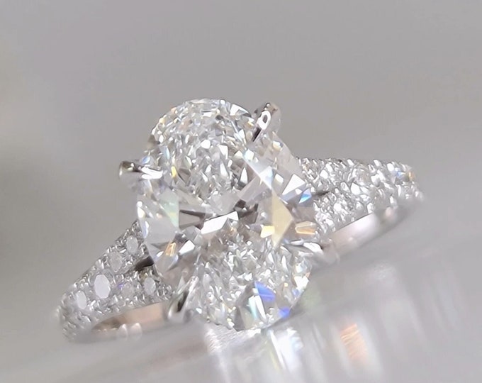 This unique 14K white gold split shank diamond pave setting with hidden accents features a 3 carat oval cut IGI certified CVD lab grown diamond and 0.70ct accent diamonds
