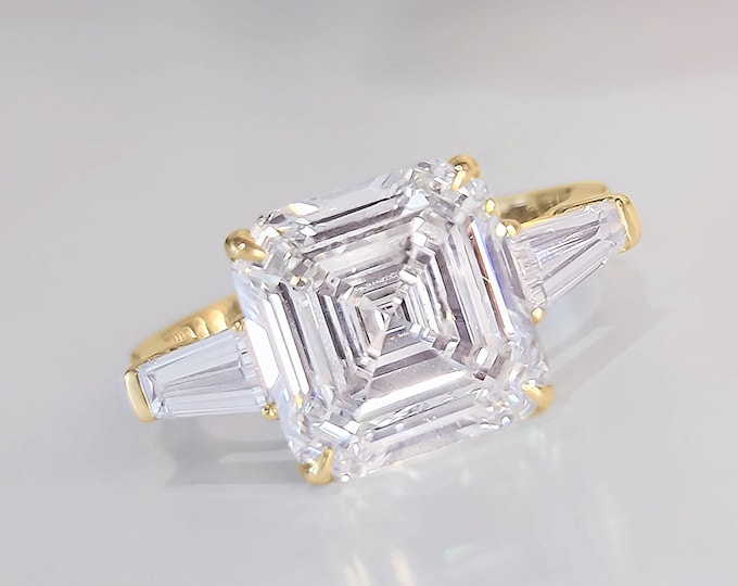 This timeless classic 3 stone ring features a 5 Carat Asscher Cut IGI certified CVD lab grown Diamond and 0.70 carats tapered baguette side stones