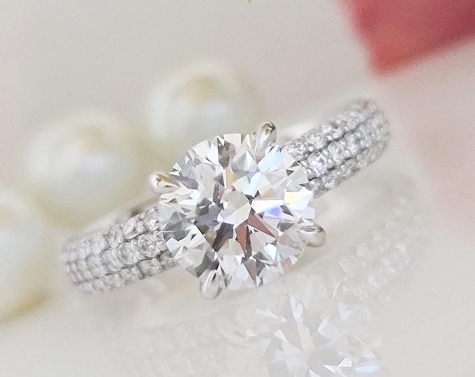 This unique wide band multi row pave diamond setting features a 2 carat round cut IGI certified CVD lab grown diamond and 0.55 carats accent diamonds