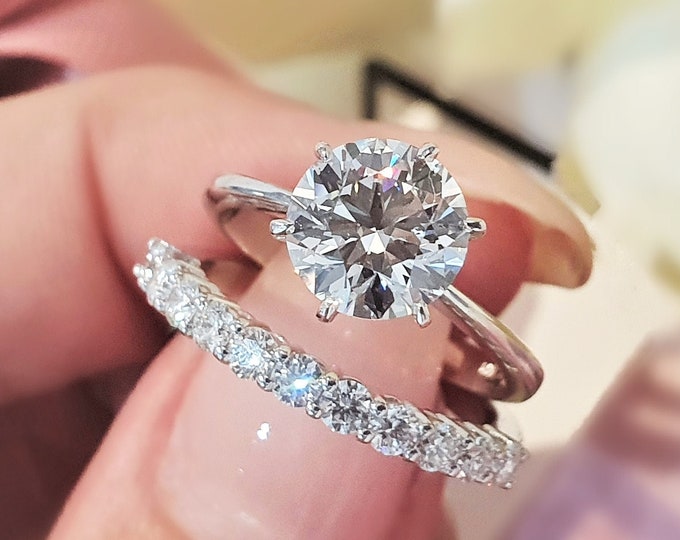 This classic timeless bridal ring set features a 14K white gold solitaire set with a 2 carat round cut IGI certified CVD lab grown diamond  accompanied by a matching 0.47ct diamond set wedding band