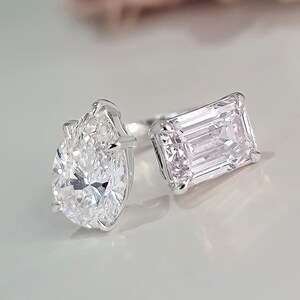 Puede incluir: Un anillo de diamante de forma pera con un diamante más pequeño de talla esmeralda en el lateral.