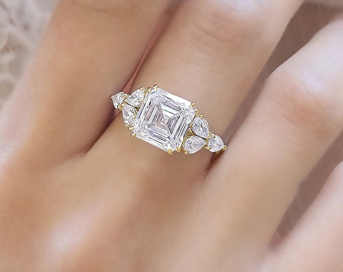 This timeless classic 3 stone ring features a 5 Carat Asscher Cut IGI certified CVD lab grown Diamond and 0.96 carats teardrop side stones