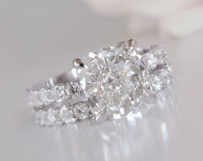 This classic 14K Gold  pave diamond setting features a 3 carat IGI certified CVD lab grown cushion cut diamond & 0.56 carats accent diamonds accompanied by a matching 0.62 carats wedding band