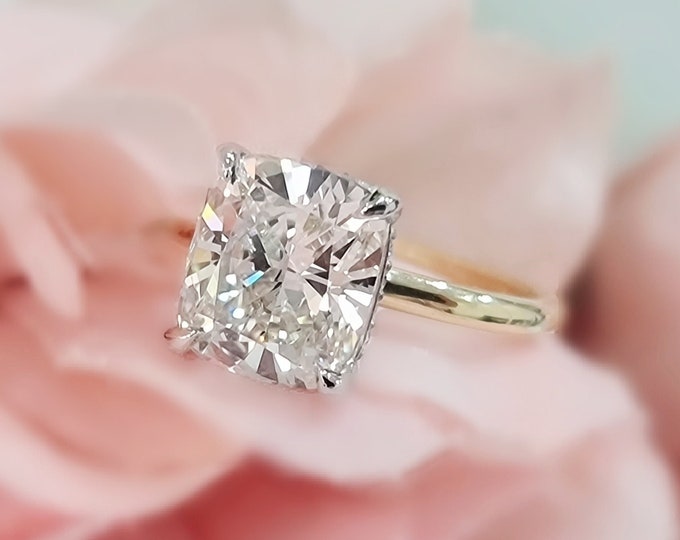 This dainty 2 tone 14K gold hidden halo setting features a 3 carat cushion cut IGI certified CVD lab grown diamond & 0.19cts accent diamonds