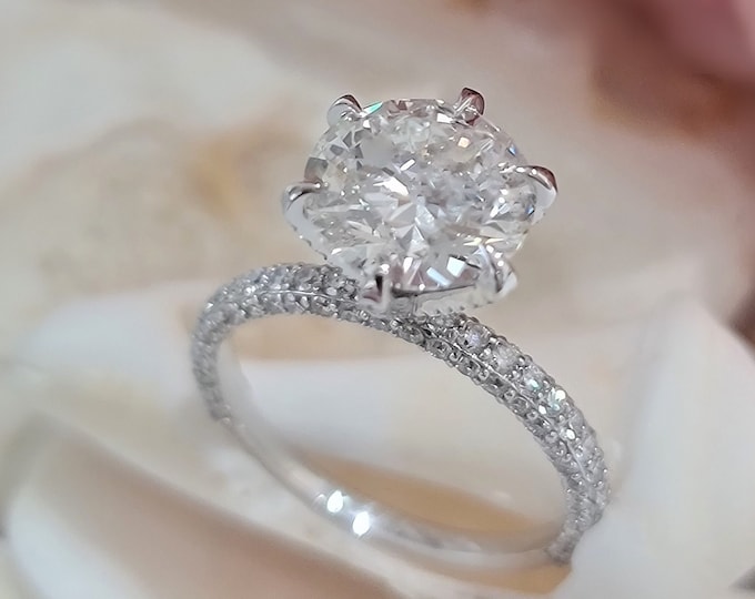 This unique ring design in 14K white gold features a 3 Carat  Round Brilliant cut IGI certified CVD lab grown diamond & 1.16 carats accent diamonds