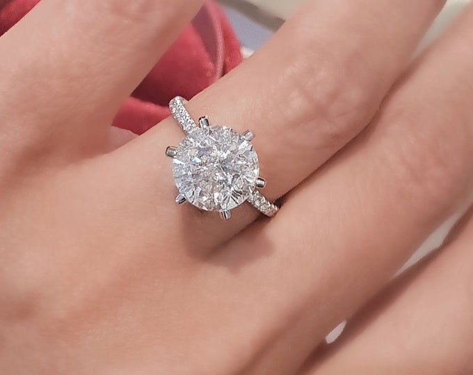 This unique diamond setting features a dainty diamond pave band & diamonds running up the prongs set with a 3 carat ideal round brilliant cut IGI certified CVD lab grown diamond