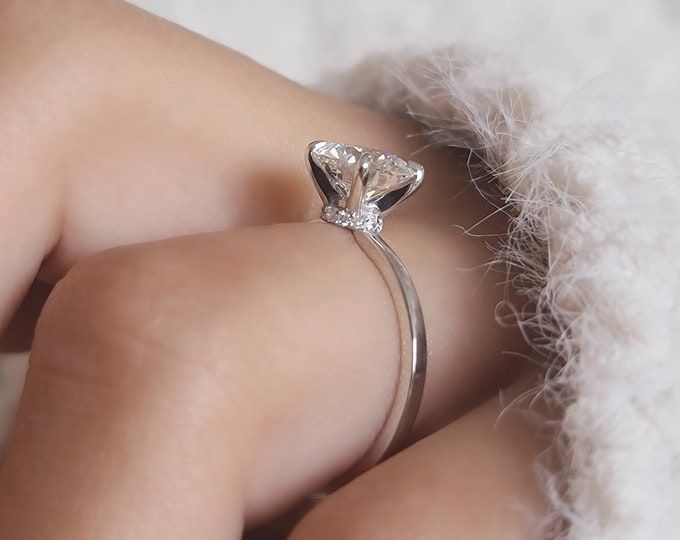 This dainty classic solitaire hidden halo diamond ring features a 1.50 carat Ideal round brilliant cut IGI certified CVD lab grown diamond