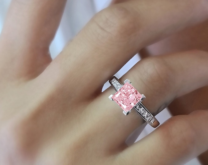 This unique channel set 14K white gold setting features a 1.5 carat pink princess cut IGI certified CVD lab grown diamond and 0.70ct princess cut side diamonds