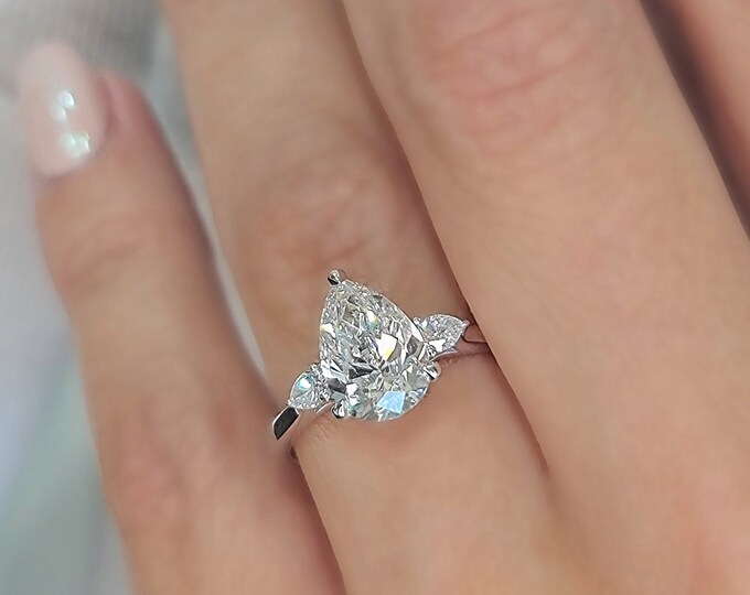 This Unique Three Stone Ring features a 2 Carat Teardrop IGI Certified CVD lab grown diamond accentuated with 0.21ct pear cut side stones