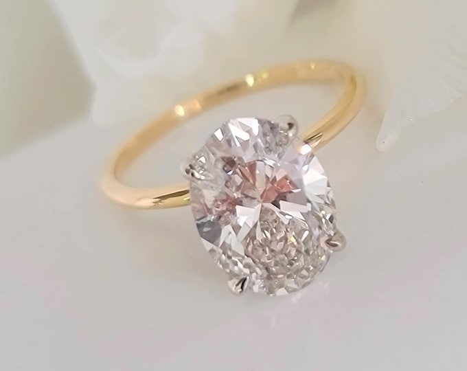This unique two tone oval engagement ring features a 3 Carat Oval cut IGI certified CVD lab grown diamond set in a 4 prong hidden halo