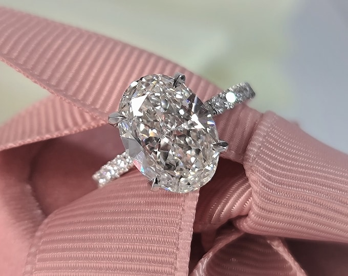 This unique hidden halo setting with pave band and hidden accents features a 3 Carat oval cut IGI certified CVD lab grown diamond
