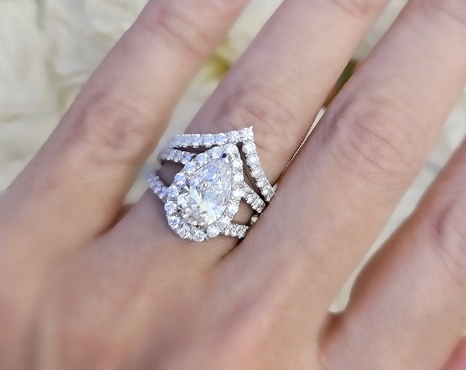 This unique ring set features  a split shank diamond pave setting with a 2.50 carat IGI certified CVD lab grown Pear cut diamond and 1.80 carat diamonds and is accompanied by a matching 0.70 carat diamond wedding  band