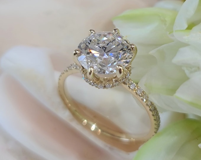 This stunning 14Kt yellow gold diamond solitaire engagement ring with hidden halo and pave diamonds on the band features a 3 carat IGI certified Ideal round brilliant cut CVD lab grown diamond and 0.33 carats accent diamonds