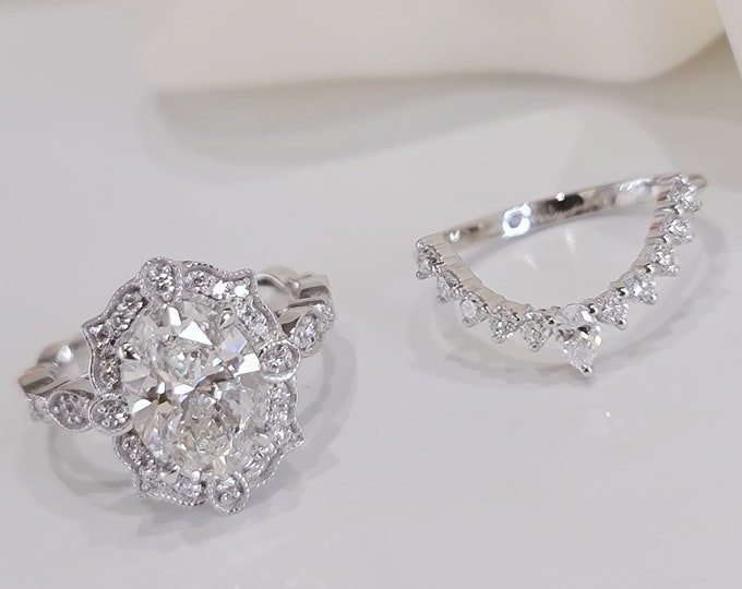 This gorgeous 14K white gold vintage Engagement ring features a 2.50 carat oval cut CVD lab grown  IGI certified diamond and 0.32 carats side stones accompanied by a matching 0.37 carats wedding band