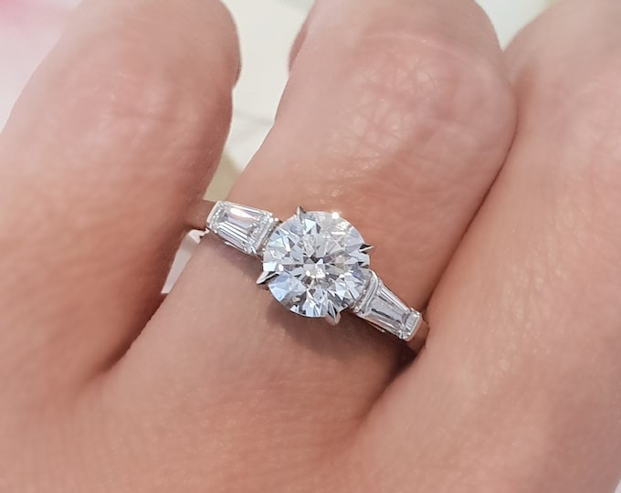 This classic three Stone Ring features a 2 Carat Round Cut IGI Certified CVD lab grown diamond accentuated with 0.40ct tapered baguette side stones