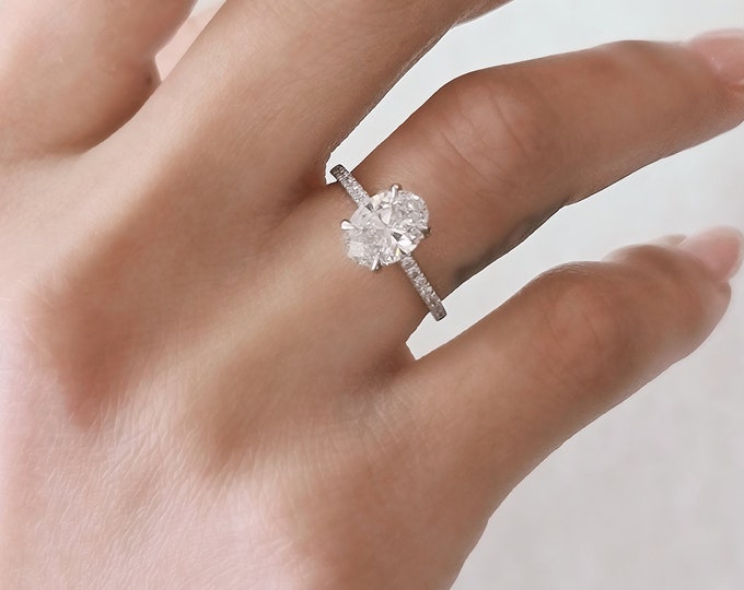 This unique oval ring with side diamonds features a 1.5 carat center oval cut IGI certified CVD lab grown diamond set with 0.18 carats side diamonds