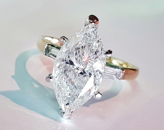 This Unique Three Stone Engagement Ring features a  3 Carat IGI Certified CVD lab grown Marquise Cut diamond accentuated  with 0.40 carats tapered baguette side diamonds