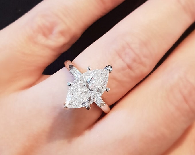 This Unique Three Stone Engagement Ring features a  3 Carat IGI Certified CVD lab grown Marquise Cut diamond accentuated  with 0.40 carats tapered baguette side diamonds