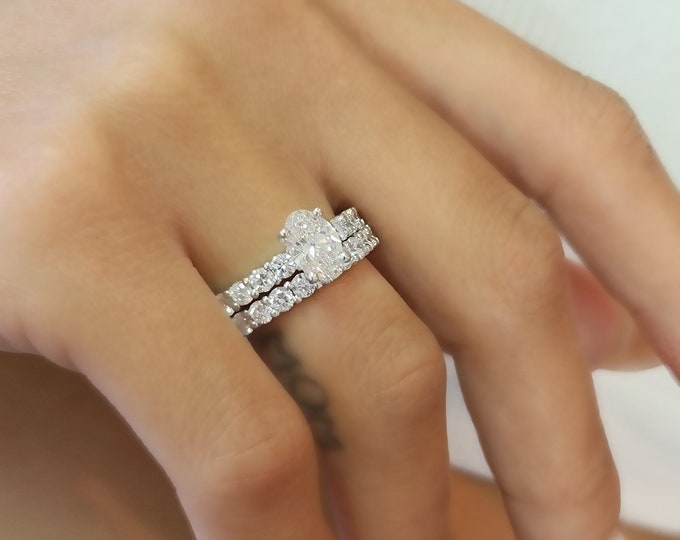 This unique oval ring with side diamonds features a 1.10 carat center oval cut IGI certified CVD lab grown diamond set with 0.90 carats side diamonds accompanied  by a 1 carat flushing matching wedding band