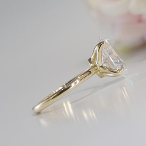 May include: A gold engagement ring with a large, clear oval-shaped diamond set in a prong setting. The band is thin and simple.