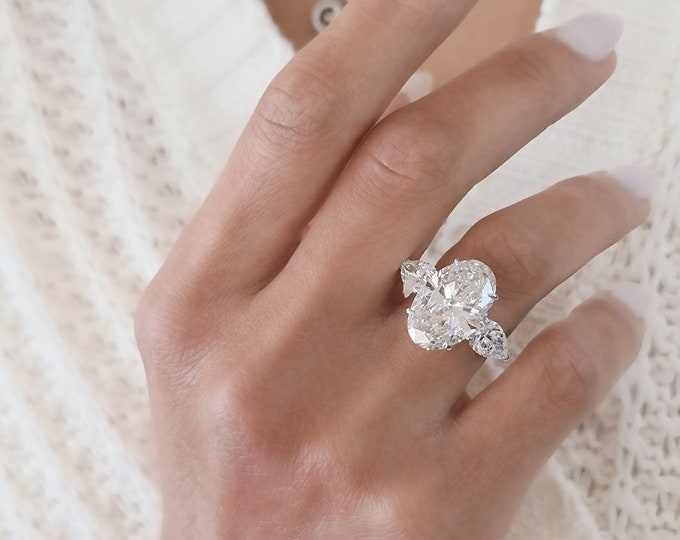 This Unique Three Stone Ring features a 7 Carat Oval Cut IGI Certified CVD lab grown diamond accentuated with 2 carats oval cut side stones