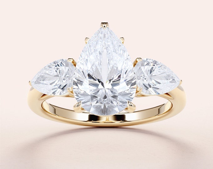 This Unique 14K yellow gold three Stone Ring features a 2 carat pear cut IGI Certified CVD lab grown diamond accentuated with 0.50ct pear cut side diamonds
